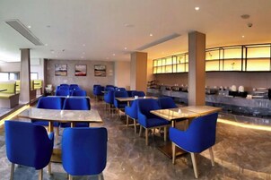 Un restaurante con sillas y mesas azules, una barra con encimera de mármol y una pared adornada con cuadros.
