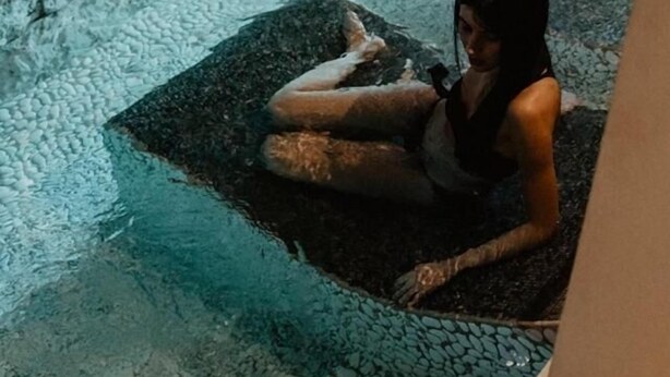 A person sitting in a stone-tiled pool area with a stone wall in the background. - Albergo Miramonti (Scanno)