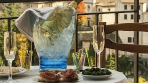 A table set with a bottle of champagne, a glass, and a plate of olives, overlooking a hillside town. - Albergo Miramonti (Scanno)
