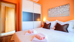 Ett hotellrum med en säng, kuddar, en garderob och en tavla på väggen.