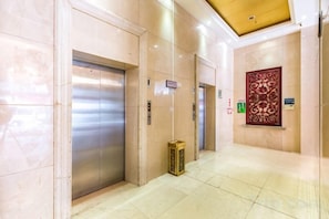 Eine Hotelhalle mit Aufzügen, einer Rezeption und einem dekorativen Wandbild.