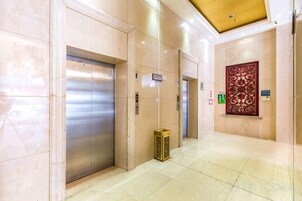Atrio di un hotel con ascensori, una reception e un pannello decorativo.