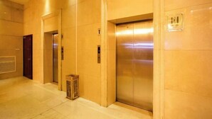 A hallway with three elevators and a door on the left. - Hengdian World Studios Xinghe Grand Hotel (Ming and Qing Palace Scenic Area) (Dongyang)