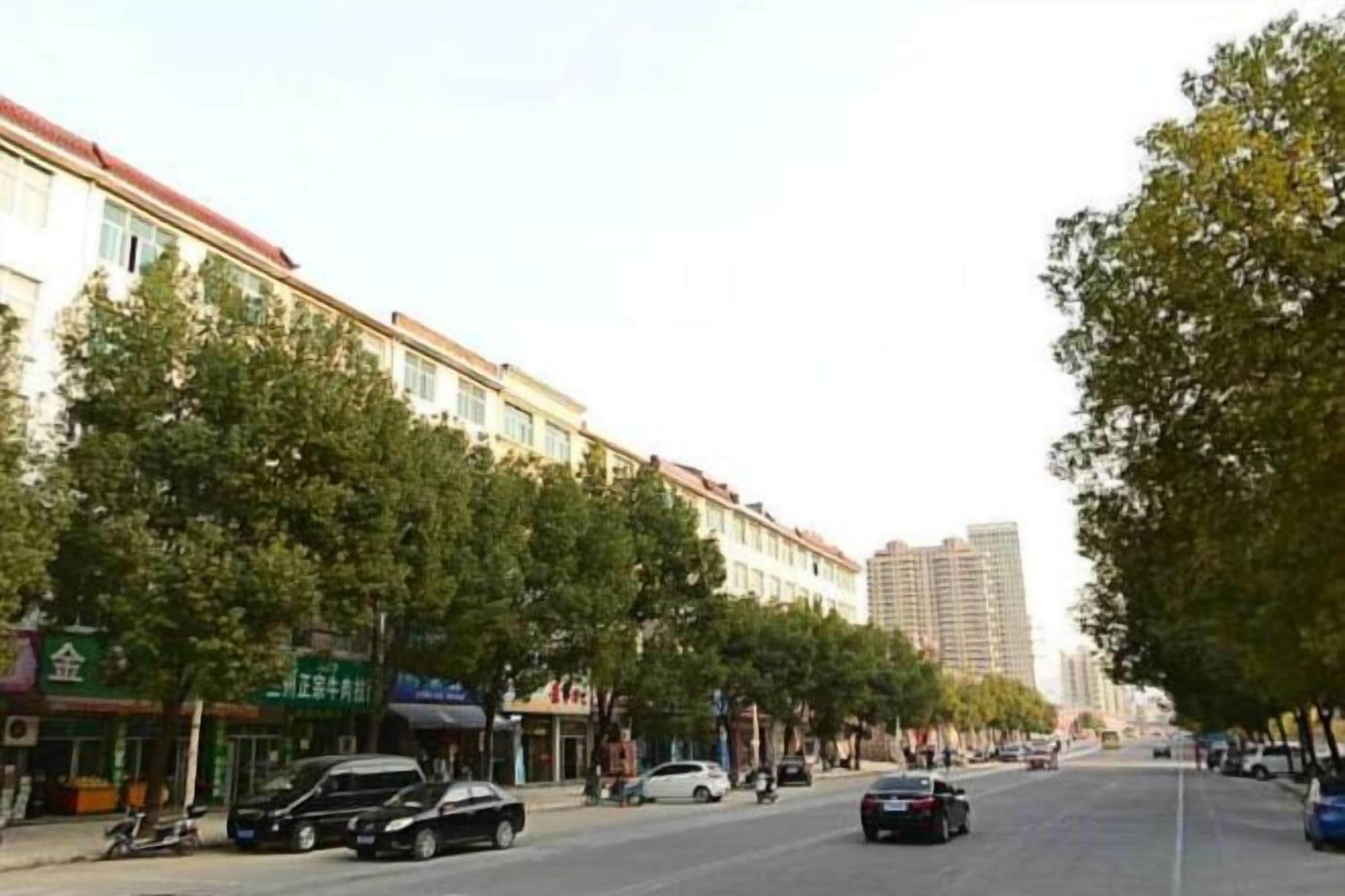 Una calle bordeada de árboles y edificios, con coches estacionados al costado.