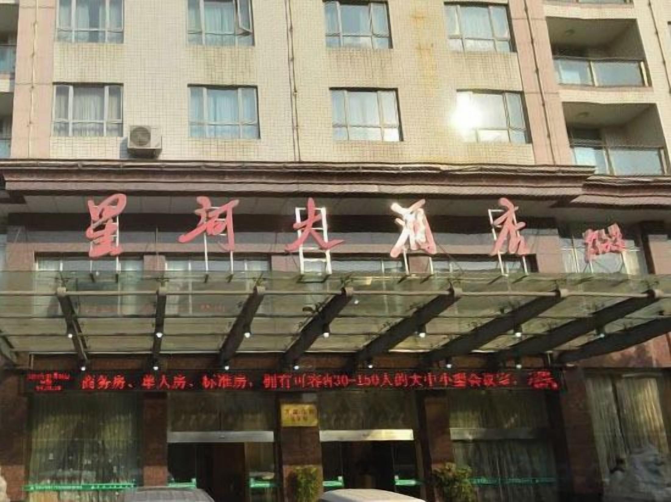 A hotel with a glass entrance and a sign with Chinese characters.