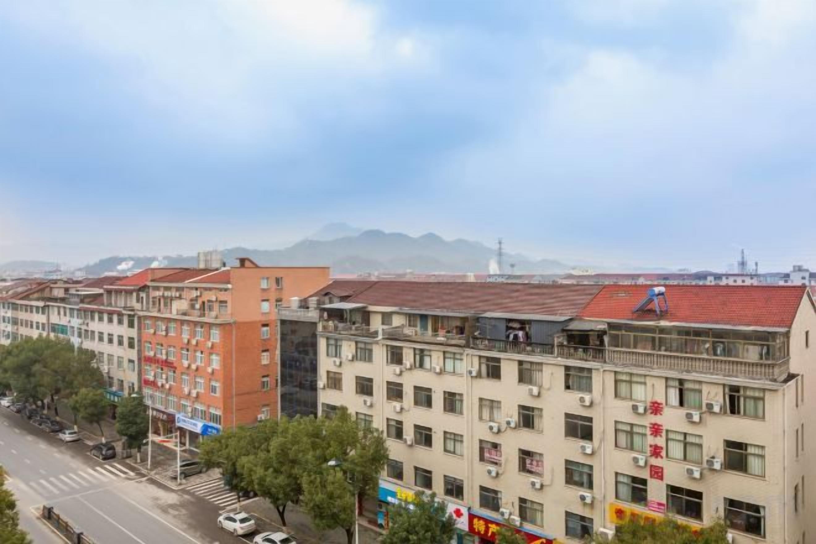A multi-story building with a flat roof, several air conditioning units, and a street in front.