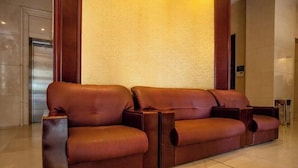 A brown leather sofa in a lobby with a marble floor and a wooden column. - Hengdian World Studios Xinghe Grand Hotel (Ming and Qing Palace Scenic Area) (Dongyang)
