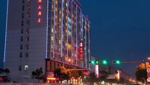 A multi-story hotel with illuminated signage and a modern facade. - Hengdian World Studios Xinghe Grand Hotel (Ming and Qing Palace Scenic Area) (Dongyang)