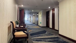 A hotel corridor with patterned walls, a carpeted floor, and a row of doors on one side. - Hengdian World Studios Xinghe Grand Hotel (Ming and Qing Palace Scenic Area) (Dongyang)