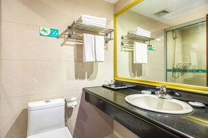 Un baño de hotel con inodoro, lavamanos y espejo.