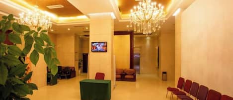 Un vestíbulo de hotel con mostrador de recepción, zona de estar y una pantalla de televisión.