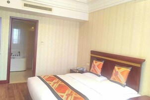 A hotel room with a bed, a nightstand, a telephone, and a bathroom visible through an open door.