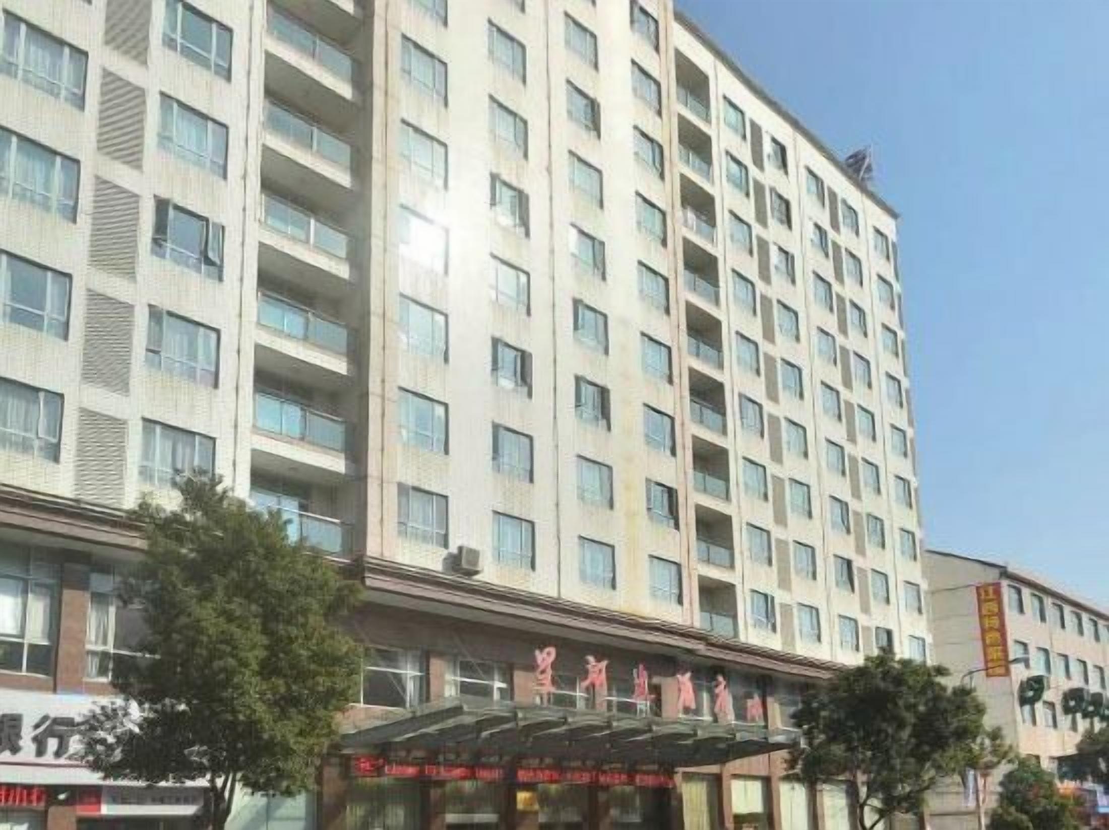 A multi-story hotel with a modern facade, a covered entrance, and a clear sky.