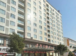 Um hotel com vários andares, fachada moderna, entrada coberta e céu claro.