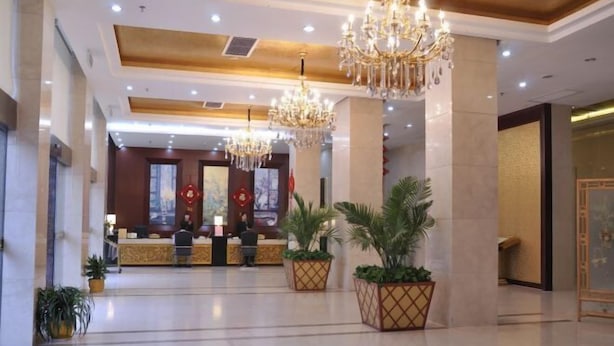 A hotel lobby with a reception desk, chandeliers, and potted plants. - Hengdian World Studios Xinghe Grand Hotel (Ming and Qing Palace Scenic Area) (Dongyang)