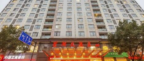 A multi-story hotel with a prominent entrance, a visible signboard, and a clear view of the surrounding area.