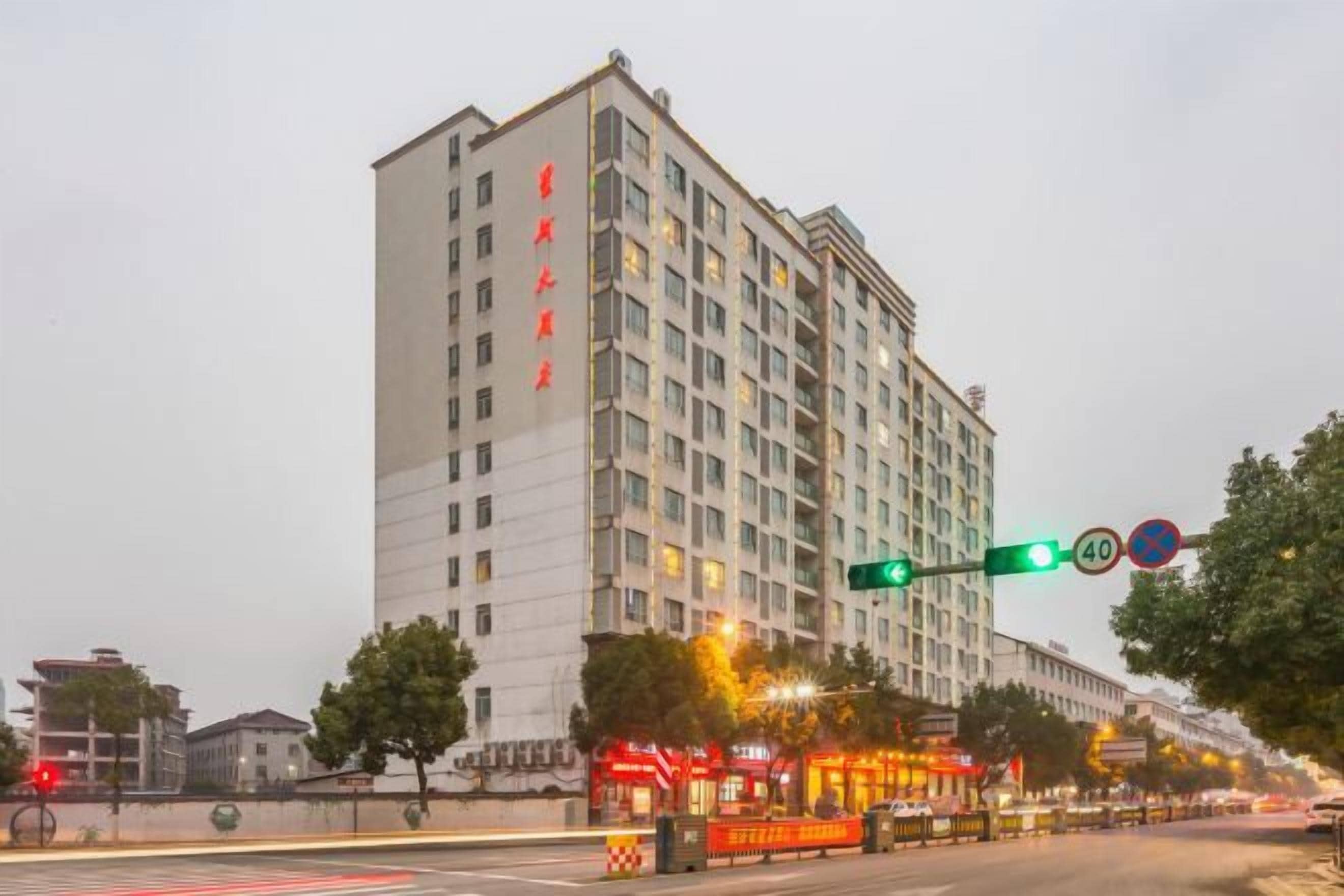 Un hôtel à plusieurs étages, doté d’une entrée imposante, d’un passage piéton et de panneaux de signalisation indiquant une limite de vitesse et interdisant le stationnement.