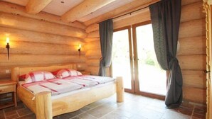 Camera da letto in una baita di legno, con un letto in legno, due comodini e una porta scorrevole in vetro che dà sull'esterno.