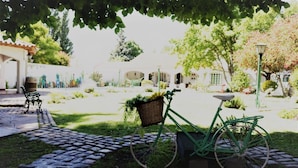 A courtyard with a green bicycle, a wicker basket, and a stone pathway. - Chiara Lodge (Chacras de Coria)