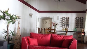 A spacious living room with a red sofa, a glass coffee table, and a wooden floor. - Chiara Lodge (Chacras de Coria)