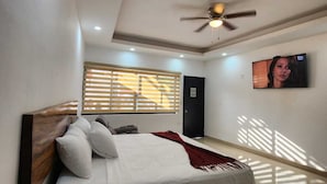 A bedroom with a bed, a ceiling fan, a TV, and a window with blinds. - Yolonam Inn (Tuxtla Chico)