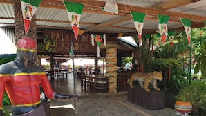 A restaurant with a covered patio, a statue of a man, and a leopard statue. - Yolonam Inn (Tuxtla Chico)