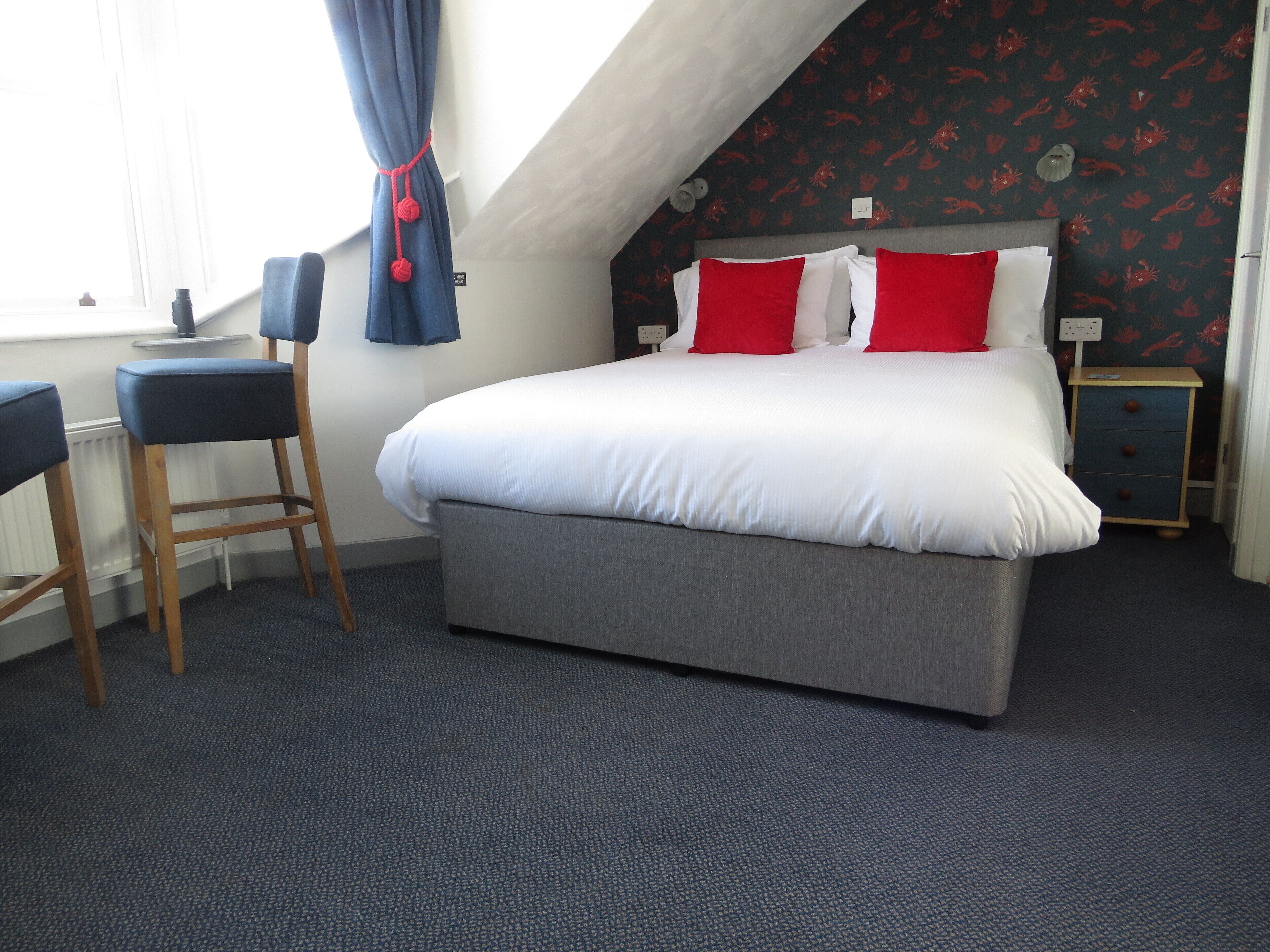 A bedroom with a bed, two nightstands, a desk, and a chair.
