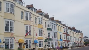 A row of colorful terraced houses with flags, a pub, and a shop. - Brunswick Bed & Breakfast (Weymouth)