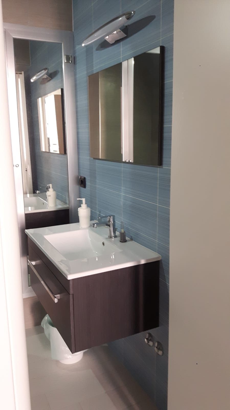 A modern bathroom with a large mirror, two sinks, and a vanity.
