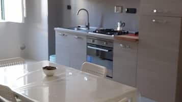 Una cucina moderna con mobili bianchi, un piano cottura a gas e un tavolo con sedie.