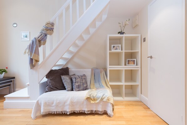 A bedroom with a bed, a white staircase, a white shelving unit, and a door.