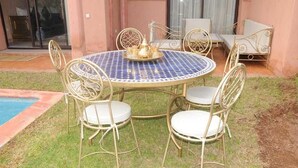 A round outdoor table with four chairs, a decorative tray, and a glass door in the background. - Villa Jasmine V4 70 Marrakesh (Marrakech)