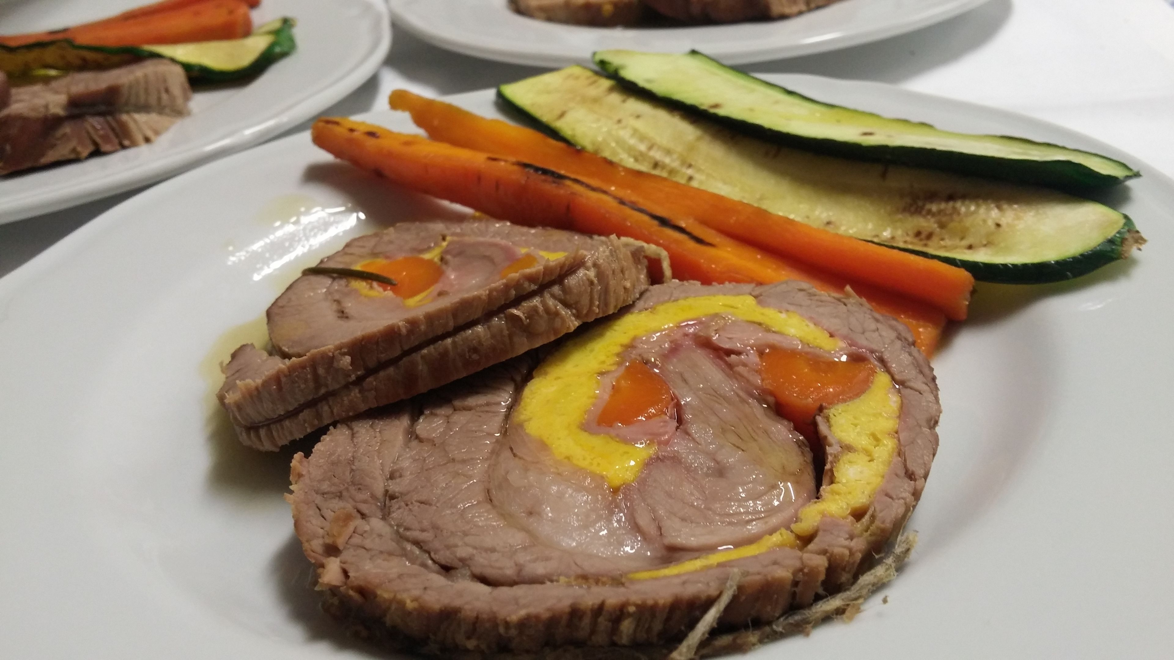 A plate with sliced meat, vegetables, and a sauce.
