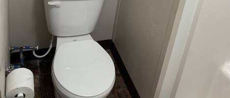 A small bathroom with a toilet, a towel rack with two towels, and a toilet paper holder.