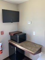 A compact kitchen with a microwave, a small refrigerator, and a built-in oven.