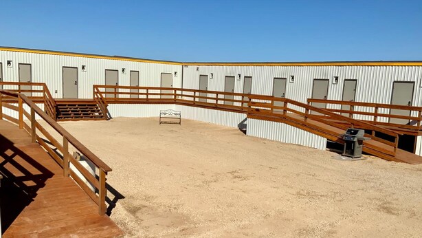 A covered equestrian arena with wooden railings and a sandy floor. - Karbani Inn (Carlsbad)