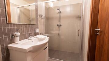 Un baño moderno con ducha envuelta en vidrio, un lavabo blanco y un espejo.