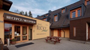 A hotel reception area with a reception desk, a wooden bench, and a clear sky.