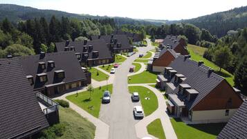 Stunning homes line the driveway, surrounded by lush lawns and rolling hills.