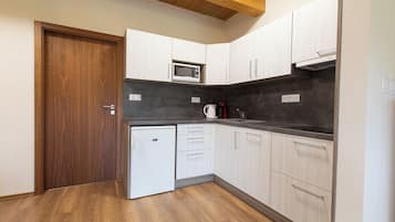 A compact kitchen with white cabinets, a microwave, a coffee maker, and a small refrigerator.