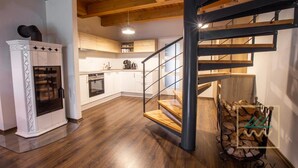 A modern kitchen with white cabinets, a built-in oven, and a wooden staircase. - Wellness hotel Říčky (Rícky v Orlických horách)
