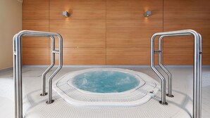 A hot tub with metal railings, a wooden wall, and a tiled floor. - Wellness hotel Říčky (Rícky v Orlických horách)