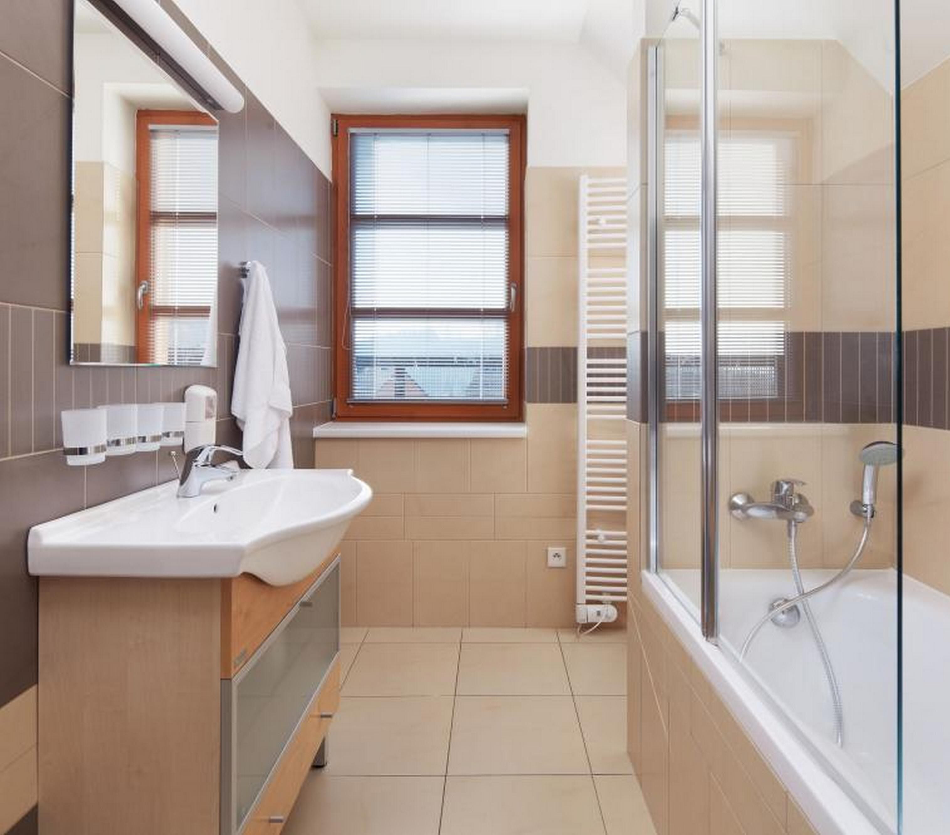 Un baño moderno con lavamanos, espejo, ventana y ducha.