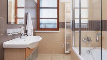 Un baño moderno con lavamanos, espejo, ventana y ducha.