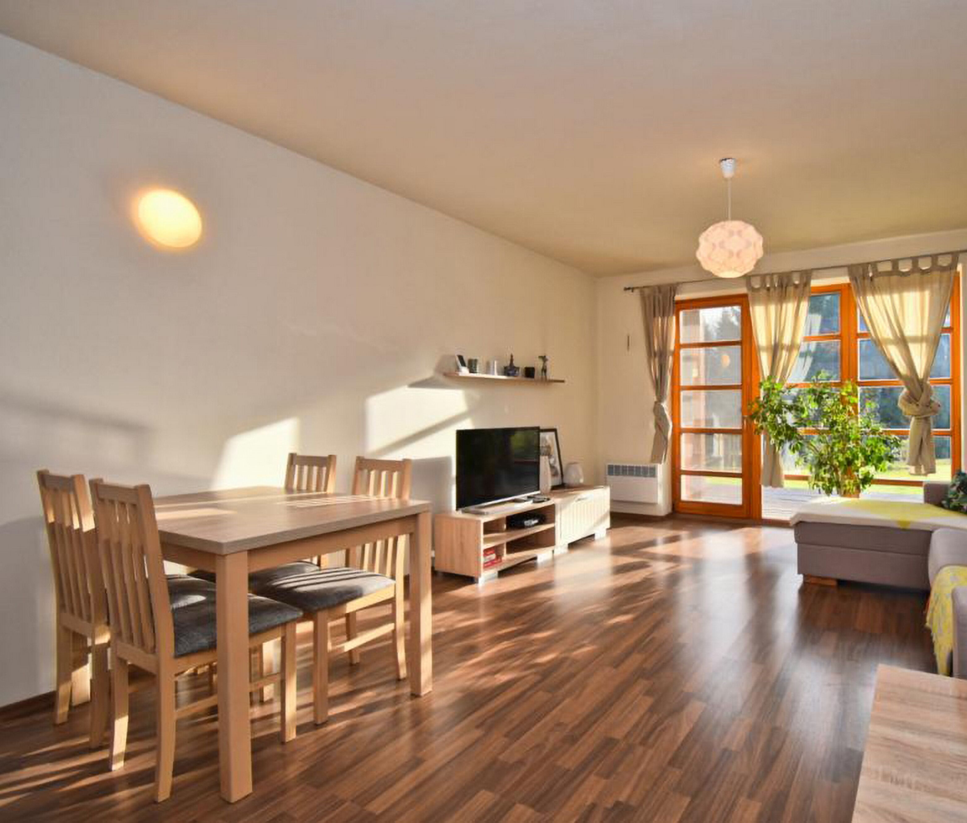 A living room with a wooden dining table, chairs, a TV, and a sofa.