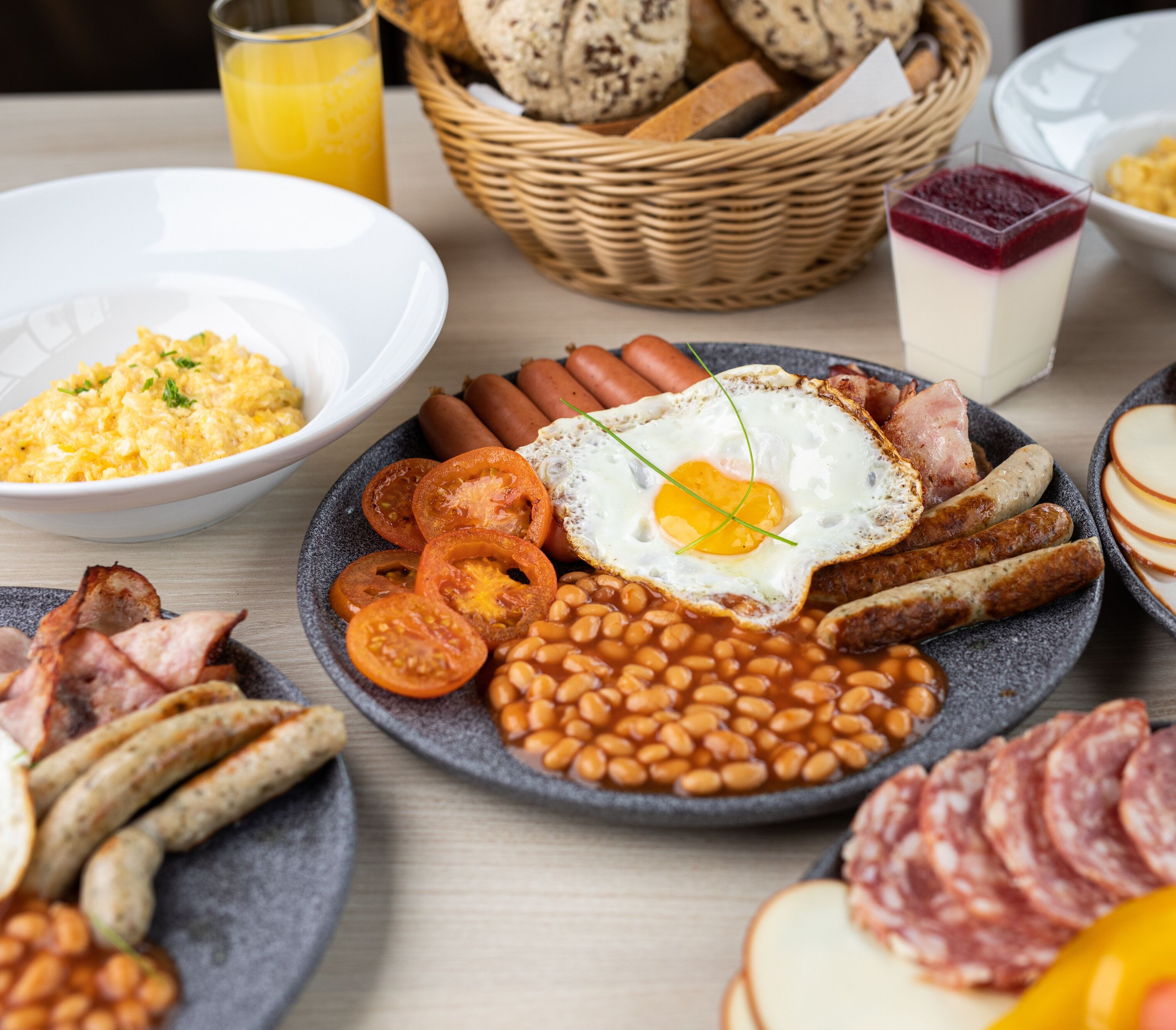A breakfast spread with eggs, sausages, beans, and various meats.