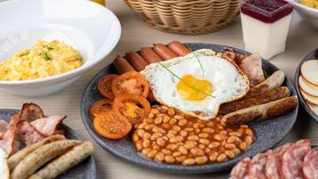 A breakfast spread with eggs, sausages, beans, and various meats.