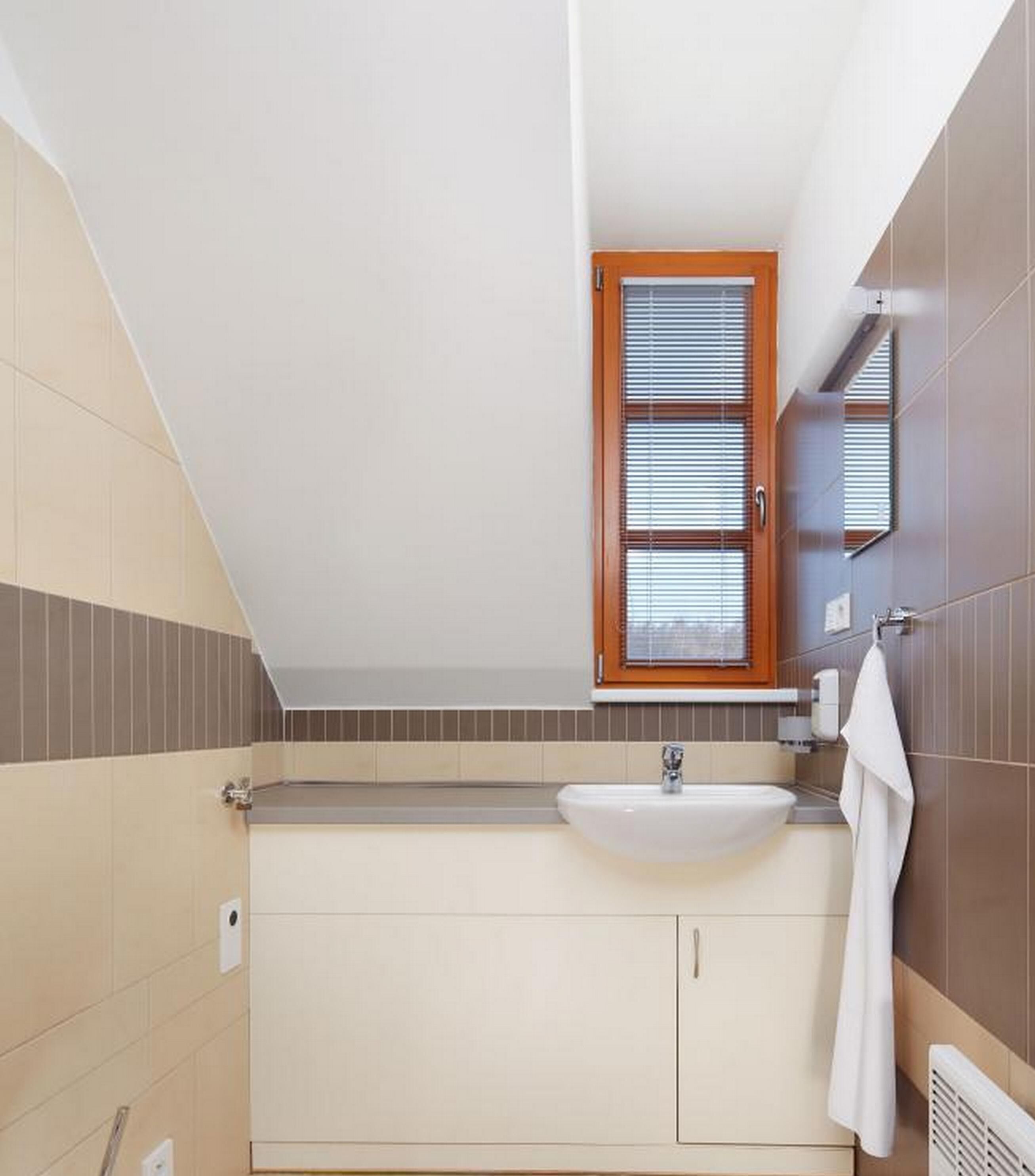 Un baño moderno con un lavamanos independiente, una ventana con persianas y una toalla colgada en la pared.