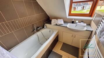 Un baño moderno con bañera, lavamanos y ventana.
