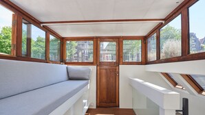 A sunlit room with a wooden bench, a door, and large windows.